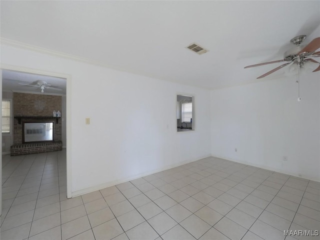 unfurnished room featuring a brick fireplace, ceiling fan, and light tile patterned flooring