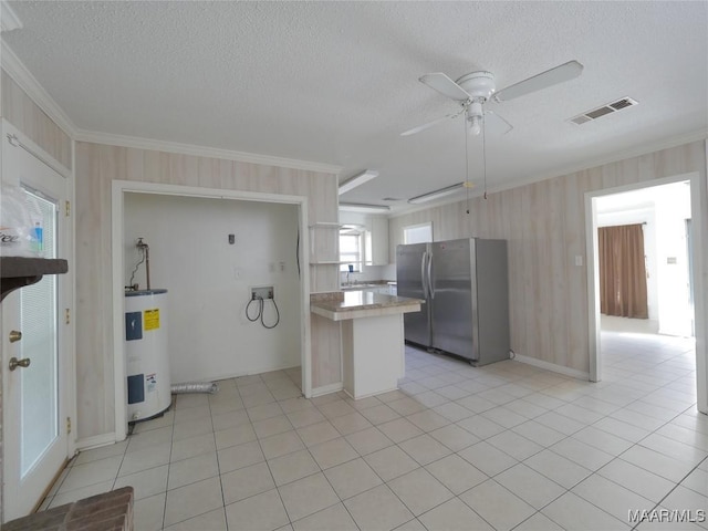 kitchen featuring light tile patterned flooring, crown molding, a textured ceiling, stainless steel refrigerator, and electric water heater