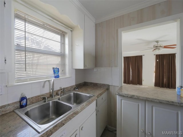 kitchen with sink, white cabinets, backsplash, ornamental molding, and ceiling fan