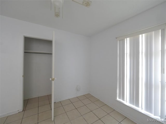 unfurnished bedroom featuring light tile patterned flooring, a closet, and multiple windows