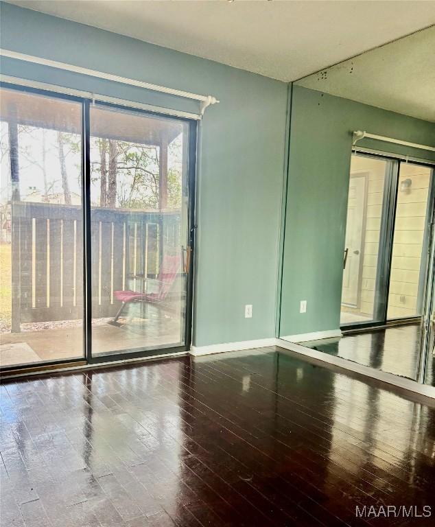 spare room featuring baseboards and wood finished floors