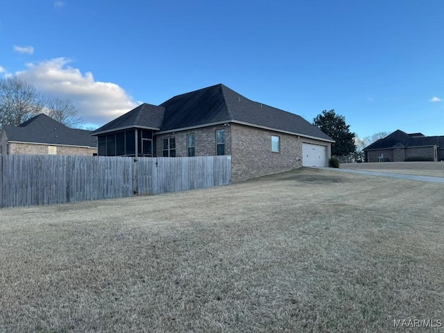 view of home's exterior featuring a garage, a lawn, and a sunroom