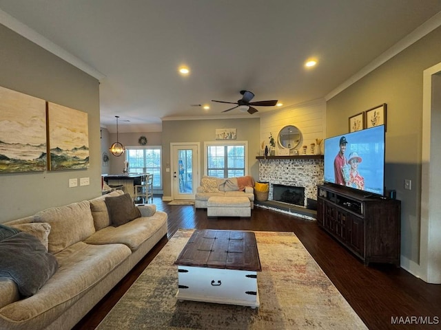 living room featuring dark wood-type flooring, ornamental molding, a tile fireplace, and ceiling fan