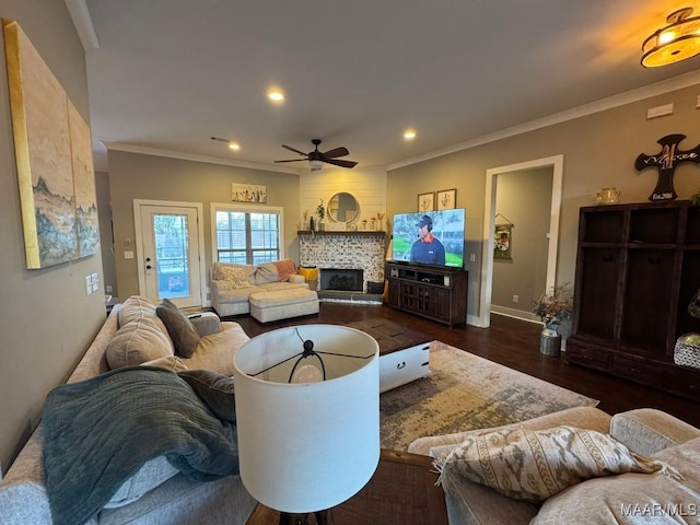 living room featuring a tiled fireplace, crown molding, ceiling fan, and dark hardwood / wood-style flooring