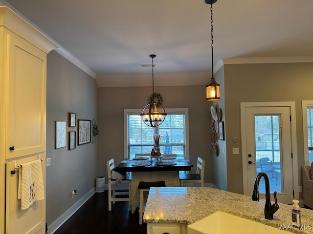 kitchen with dark hardwood / wood-style floors, decorative light fixtures, sink, crown molding, and light stone countertops