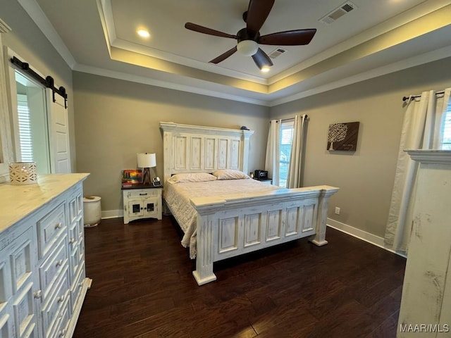 bedroom with a raised ceiling, ornamental molding, a barn door, and dark wood-type flooring