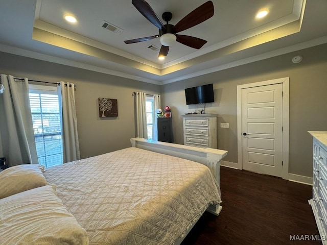 bedroom with ornamental molding, dark hardwood / wood-style floors, and a tray ceiling