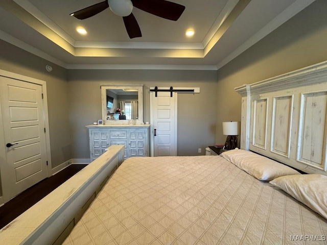 bedroom featuring ceiling fan, ornamental molding, a tray ceiling, and a barn door