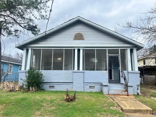 view of front of home with a sunroom and a front lawn