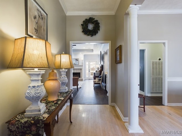 corridor with ornamental molding, decorative columns, and light wood-type flooring