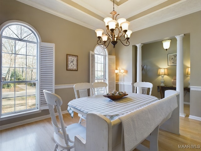 dining room with a tray ceiling, plenty of natural light, light hardwood / wood-style floors, and ornate columns