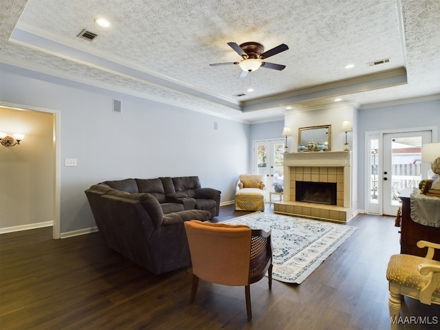 living room featuring a tray ceiling, dark hardwood / wood-style flooring, and a textured ceiling