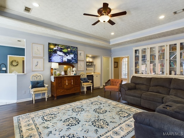 living room with dark hardwood / wood-style flooring, ornamental molding, ceiling fan, a tray ceiling, and a textured ceiling