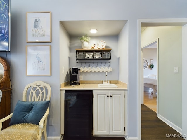 bar with white cabinetry, sink, beverage cooler, and dark hardwood / wood-style flooring