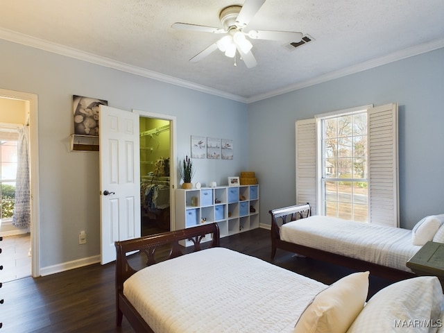 bedroom featuring dark wood-type flooring, ceiling fan, ornamental molding, a textured ceiling, and a spacious closet