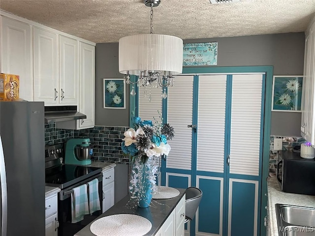 kitchen with white cabinetry, electric range oven, a textured ceiling, stainless steel fridge, and decorative backsplash