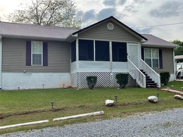 view of front of home with a sunroom, a front lawn, and metal roof