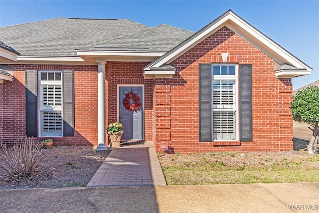 view of front of house featuring a shingled roof and brick siding