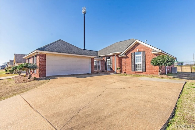 ranch-style house with an attached garage, central air condition unit, brick siding, driveway, and roof with shingles