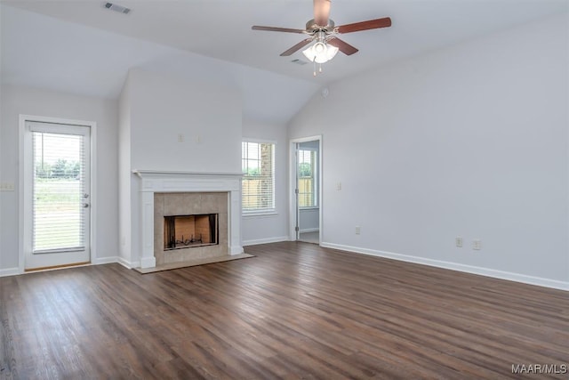 unfurnished living room featuring a tile fireplace, vaulted ceiling, a wealth of natural light, and dark hardwood / wood-style flooring