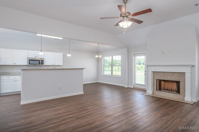 unfurnished living room with ceiling fan, lofted ceiling, dark wood-type flooring, and a fireplace