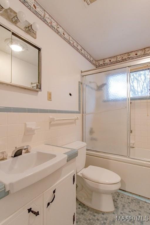 full bathroom featuring toilet, tile walls, shower / bath combination with glass door, and vanity