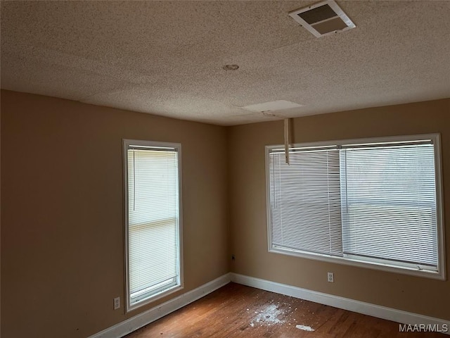 empty room with wood-type flooring and a textured ceiling