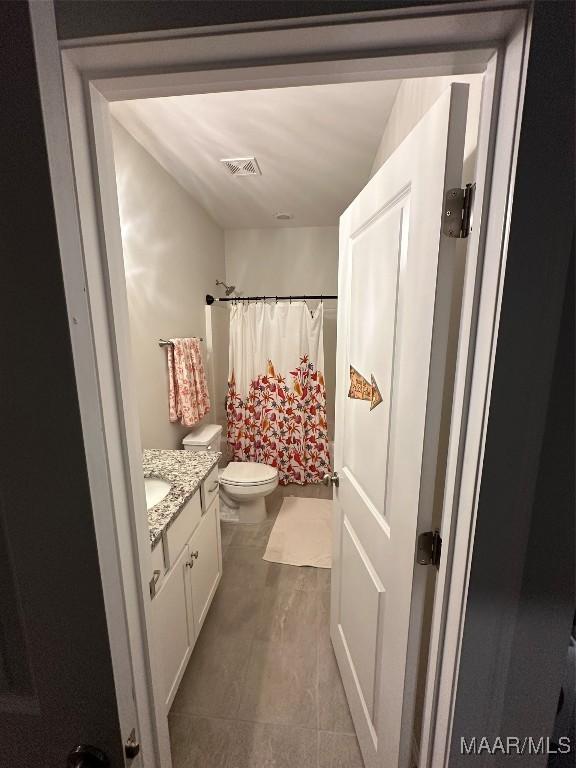 full bath with a shower with curtain, visible vents, vanity, and toilet