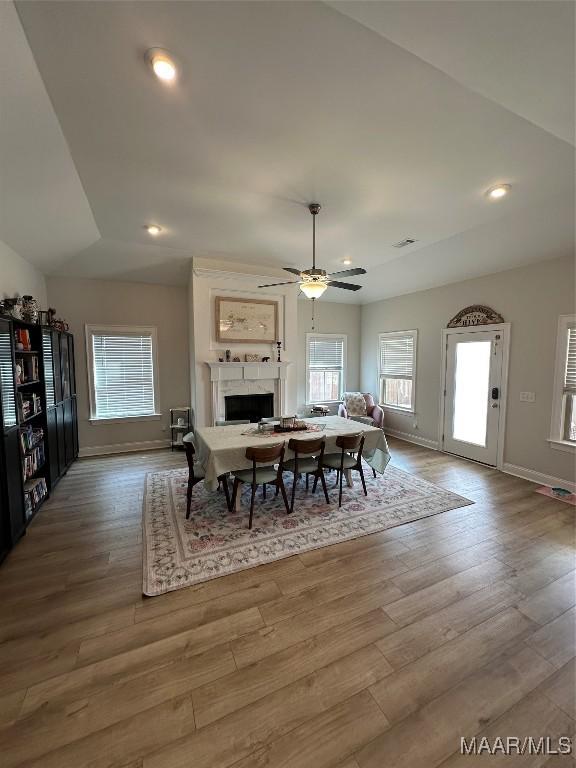 dining space with baseboards, lofted ceiling, ceiling fan, wood finished floors, and a fireplace