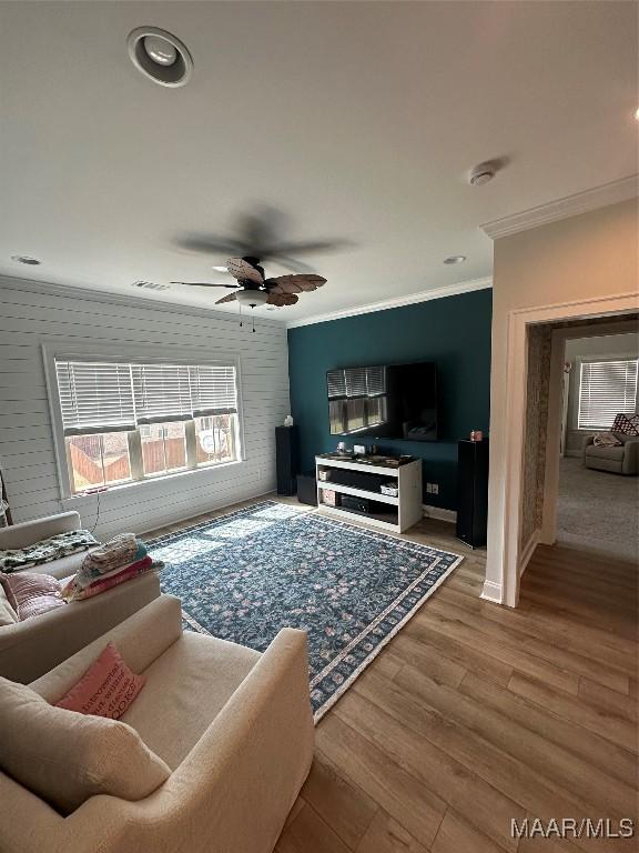 living room with ceiling fan, crown molding, and wood finished floors