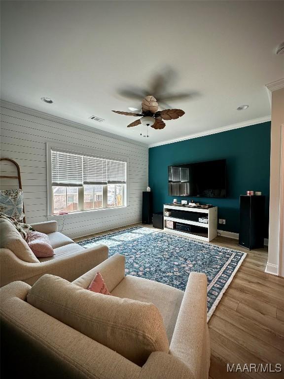 living room with visible vents, ornamental molding, a ceiling fan, wood finished floors, and baseboards