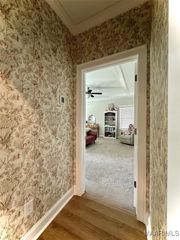 hallway with baseboards, crown molding, wood finished floors, and wallpapered walls