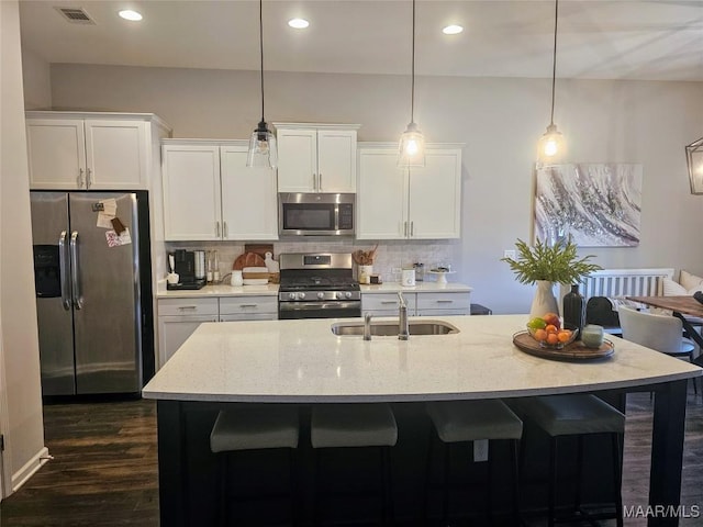 kitchen with sink, stainless steel appliances, white cabinetry, and light stone counters