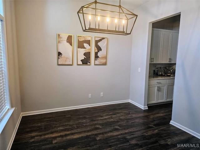 unfurnished dining area with a notable chandelier and dark hardwood / wood-style flooring