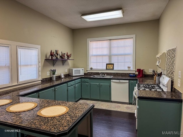 kitchen featuring white appliances, sink, green cabinets, dark hardwood / wood-style floors, and kitchen peninsula