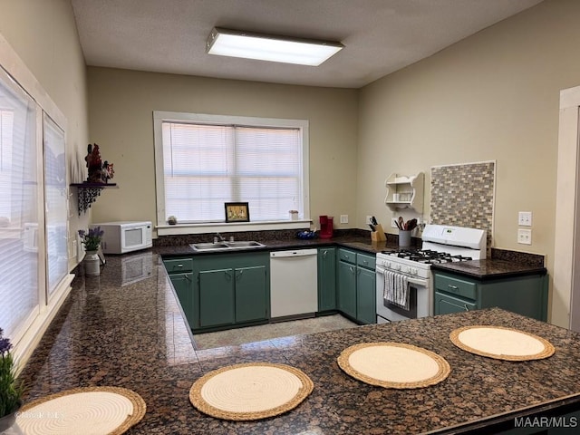 kitchen featuring sink, kitchen peninsula, white appliances, and green cabinets