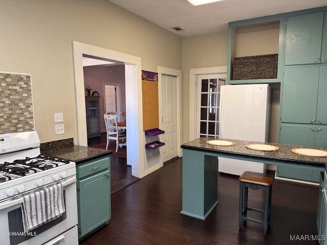 kitchen with decorative backsplash, white appliances, and dark wood-type flooring