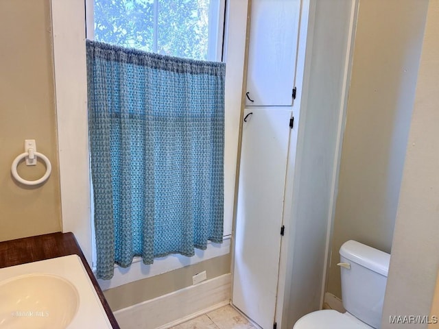 bathroom with sink, toilet, and tile patterned flooring