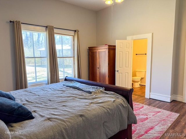 bedroom featuring ensuite bathroom and dark hardwood / wood-style flooring