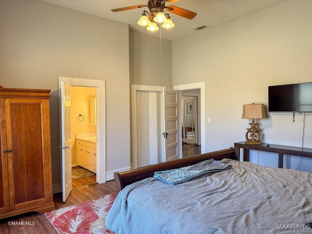 bedroom with connected bathroom, dark hardwood / wood-style flooring, and a high ceiling