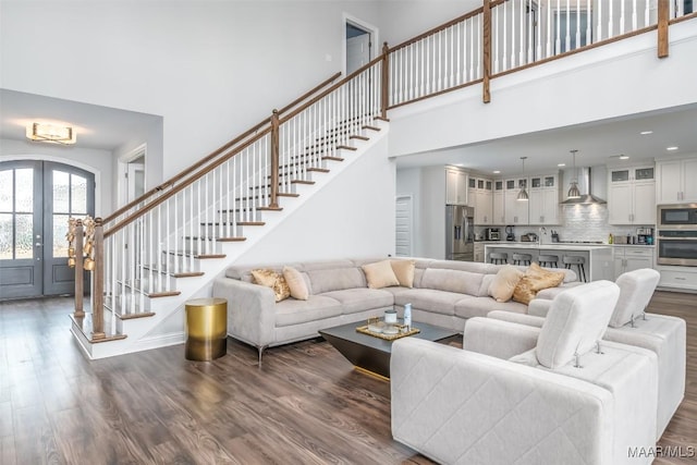 living room featuring dark wood-type flooring, a high ceiling, and french doors