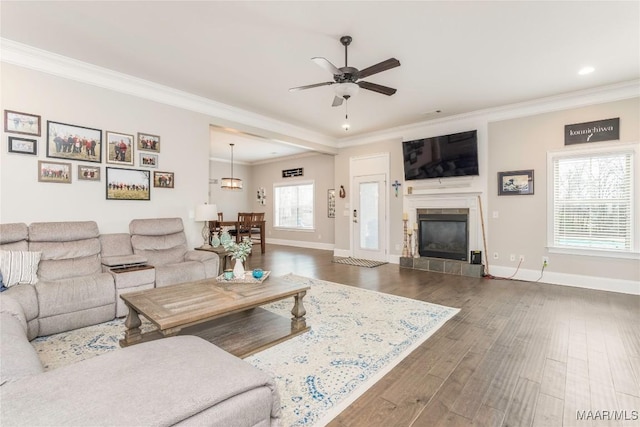 living room featuring dark wood-type flooring, a tile fireplace, crown molding, and ceiling fan