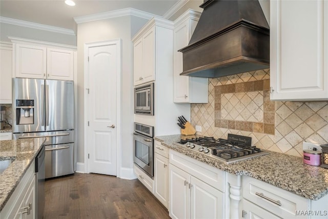 kitchen with crown molding, appliances with stainless steel finishes, white cabinetry, and custom exhaust hood