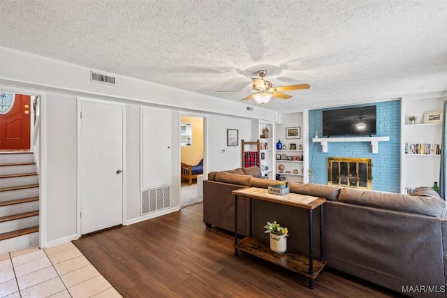 living room with hardwood / wood-style flooring, ceiling fan, a textured ceiling, and a fireplace