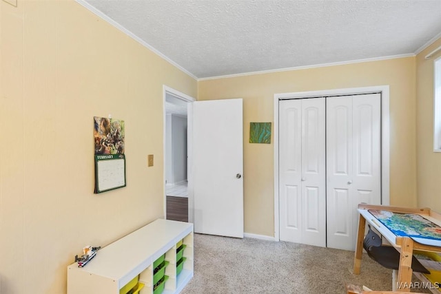 playroom featuring a textured ceiling, ornamental molding, and light colored carpet