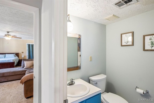 bathroom featuring a textured ceiling, toilet, vanity, and ceiling fan