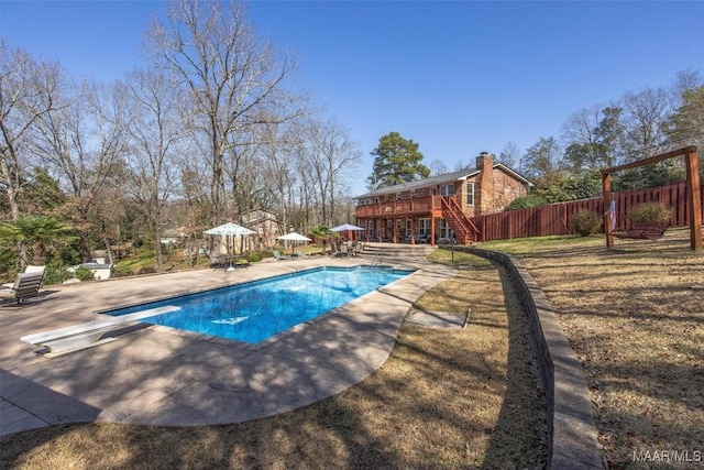 view of swimming pool with a yard, a patio, a deck, and a diving board