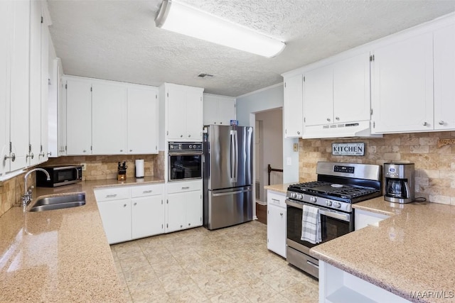 kitchen with appliances with stainless steel finishes, tasteful backsplash, a textured ceiling, white cabinets, and sink