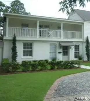 view of front facade with a front yard and a balcony