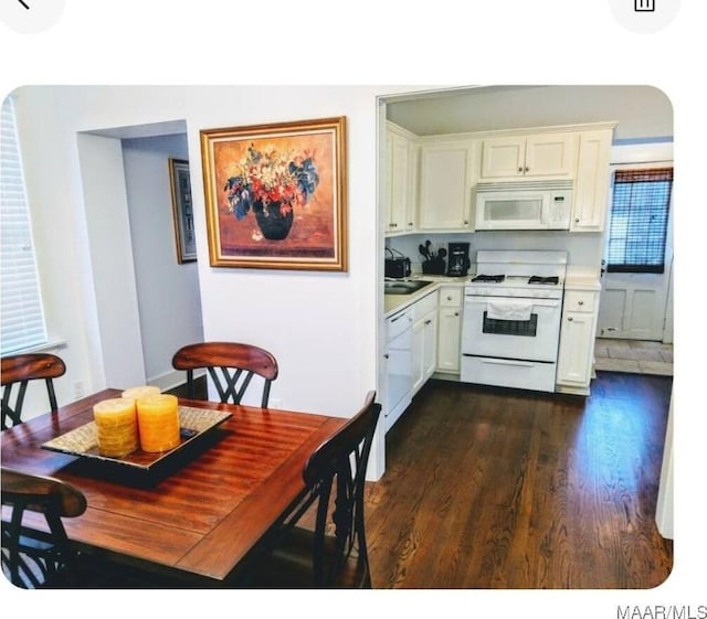 kitchen featuring white appliances, white cabinetry, and dark wood-type flooring